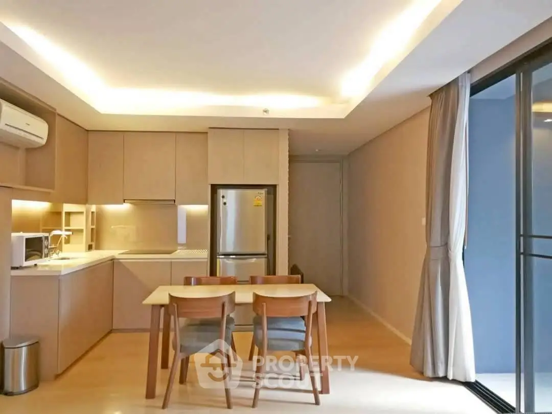 Modern kitchen with dining area, featuring sleek cabinetry and stainless steel appliances.