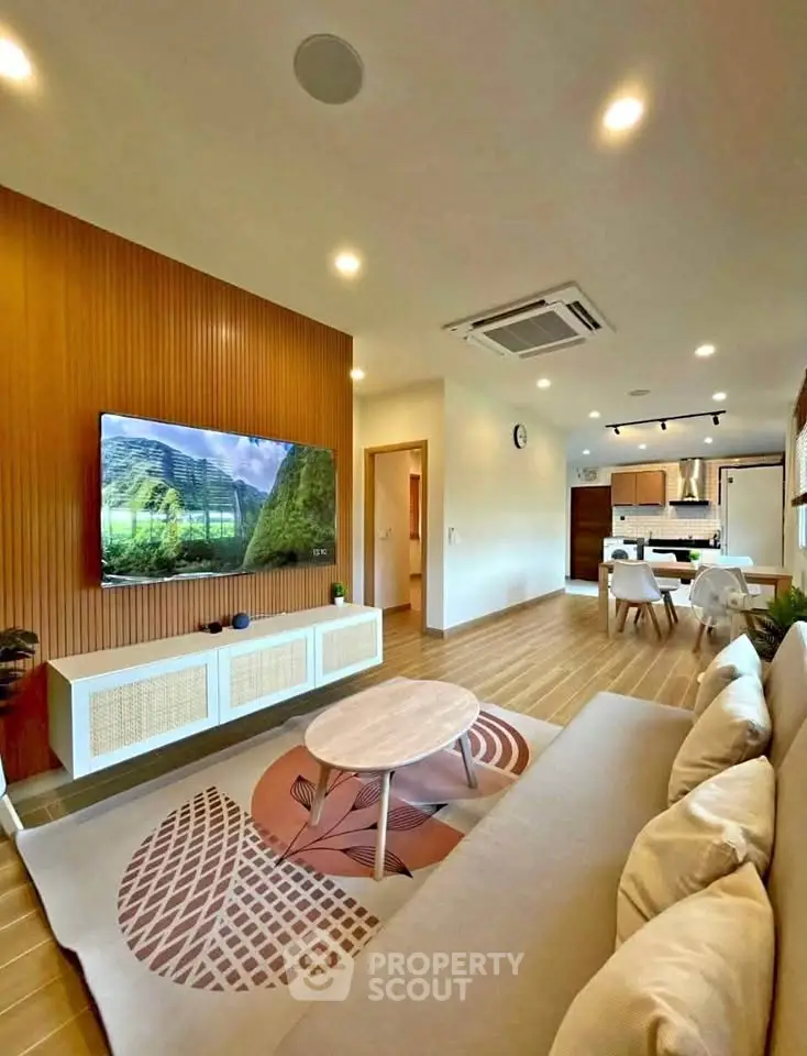 Modern living room with open kitchen, featuring stylish decor and natural lighting.