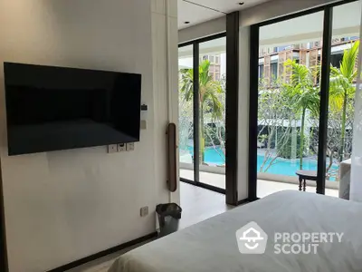 Luxurious bedroom with pool view and modern amenities in a tropical setting.