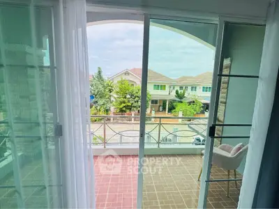 Spacious balcony with sliding glass doors offering a serene neighborhood view, perfect for relaxation.