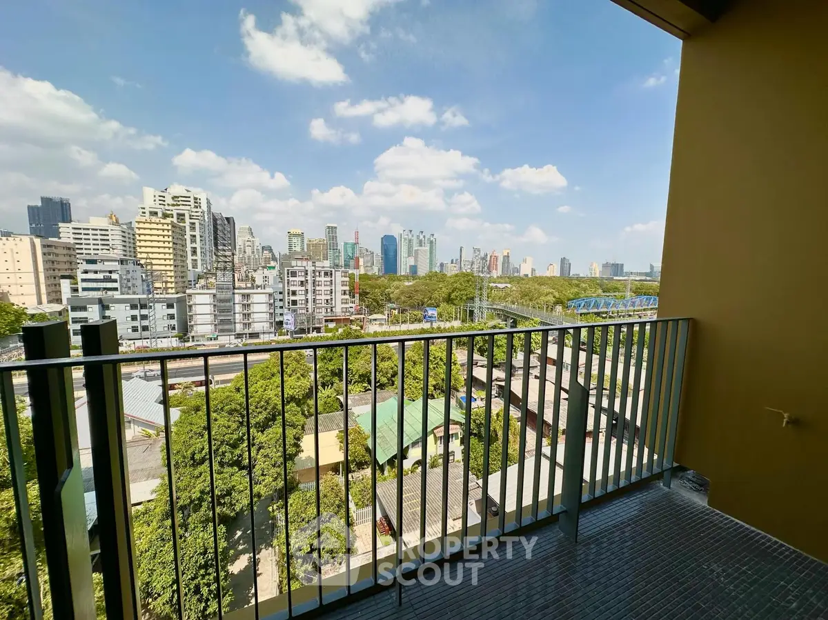 Stunning cityscape view from a modern balcony overlooking lush greenery and urban skyline.