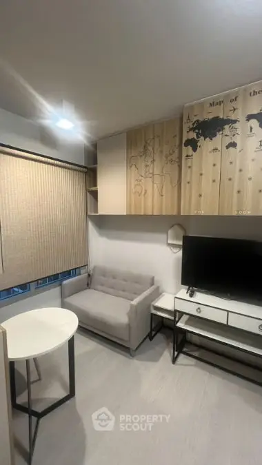 Modern living room with stylish decor and wall map, featuring a cozy sofa and sleek TV setup.