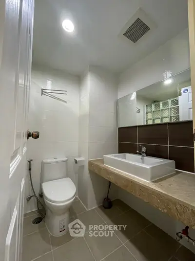 Modern bathroom with sleek fixtures and large mirror in a contemporary home.