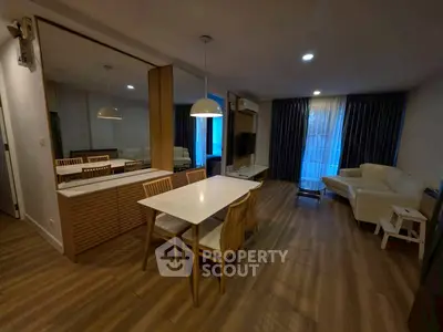 Stylish living room with modern dining area and cozy seating, featuring elegant lighting and wooden flooring.