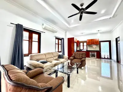Spacious living room with modern furniture and open kitchen layout in a bright, airy home.