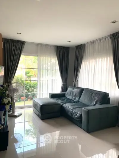 Spacious living room with large windows and modern sofa, perfect for relaxation.