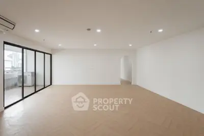 Spacious empty living room with large windows and balcony access