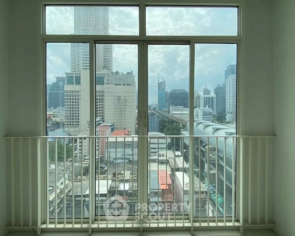 Stunning city view from a high-rise apartment balcony with large glass doors.