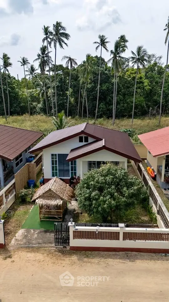 Charming tropical bungalow with lush garden and palm tree backdrop, perfect for serene living.