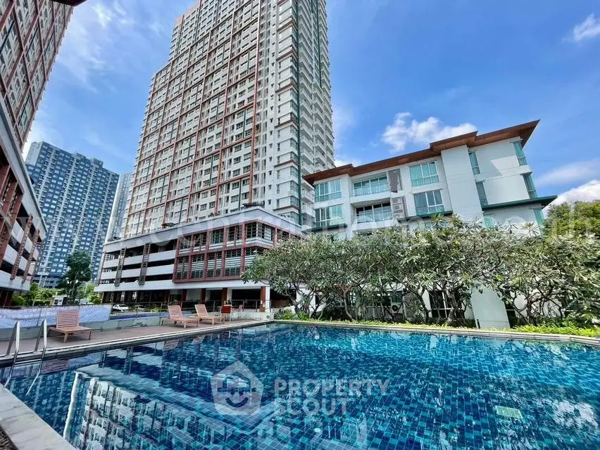 Luxurious high-rise apartment complex with stunning pool and lush greenery, perfect for modern urban living.