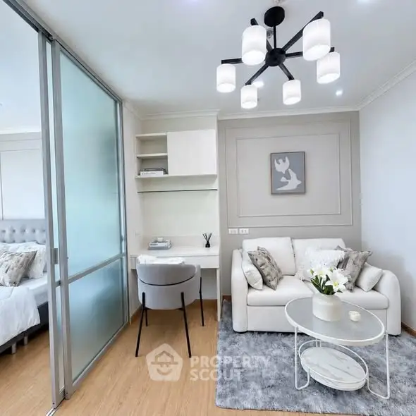 Modern living room with elegant decor and cozy seating area, featuring a stylish chandelier and sliding glass partition.