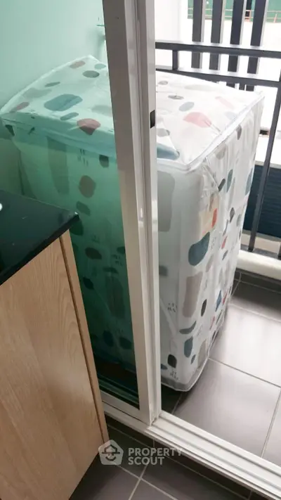 Compact balcony with washing machine and modern cover, ideal for urban living.