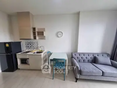 Modern compact kitchen and living area with stylish furniture and clock on wall.