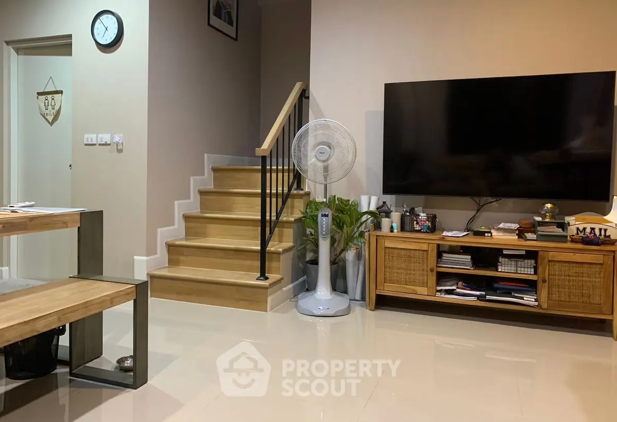 Modern living room with sleek TV setup and stylish wooden staircase
