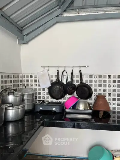 Charming kitchen with modern black countertop and hanging cookware, perfect for culinary enthusiasts.