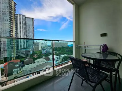 Stunning city view from a modern balcony with glass railing and cozy seating.
