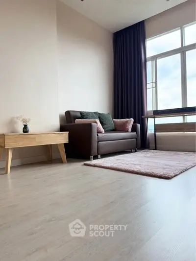 Modern living room with stylish sofa, wooden table, and large window offering natural light.