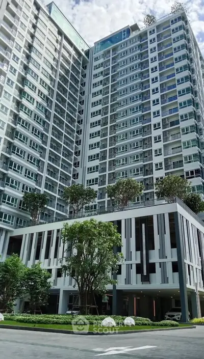 Modern high-rise building with lush greenery and sleek architectural design.