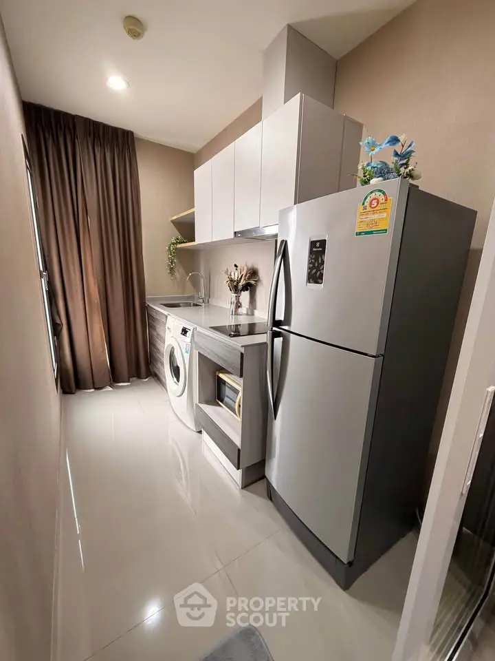 Modern kitchen with sleek appliances and washing machine in compact layout