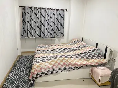 Cozy bedroom with patterned curtains and bedspread, featuring a minimalist design.