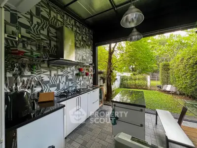 Modern open-layout kitchen with garden view, featuring sleek cabinetry and stylish backsplash.