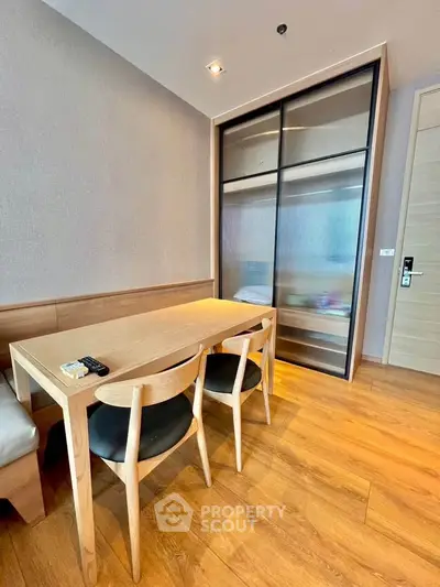 Modern dining area with wooden table and chairs, sleek storage unit, and warm lighting.