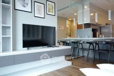 Modern living room with sleek TV setup and stylish kitchen bar area.