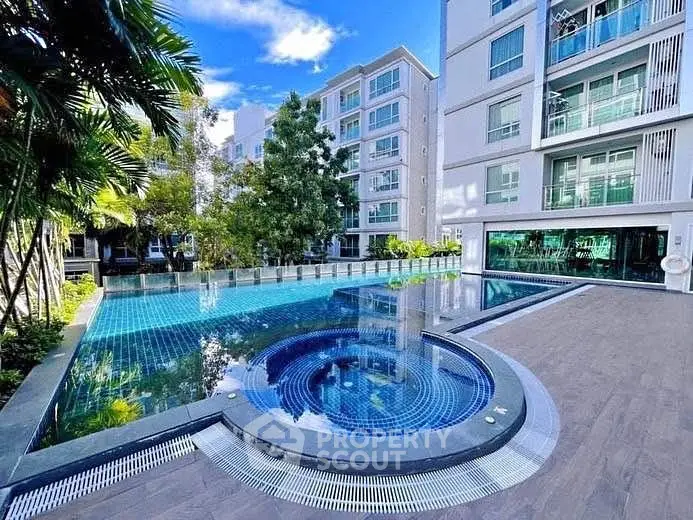 Luxurious residential pool area with modern apartment buildings and lush greenery.