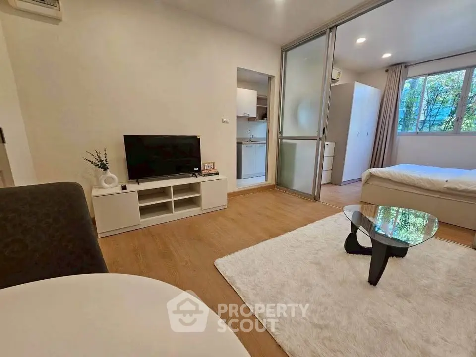Modern open-plan living room with cozy bedroom and sleek kitchen in a stylish apartment.