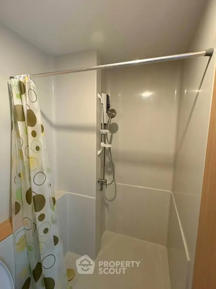 Compact bathroom with shower and modern curtain in a cozy apartment.