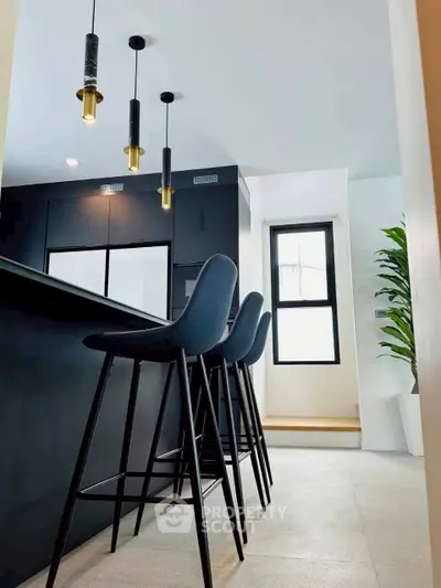 Modern kitchen with sleek black bar stools and pendant lighting