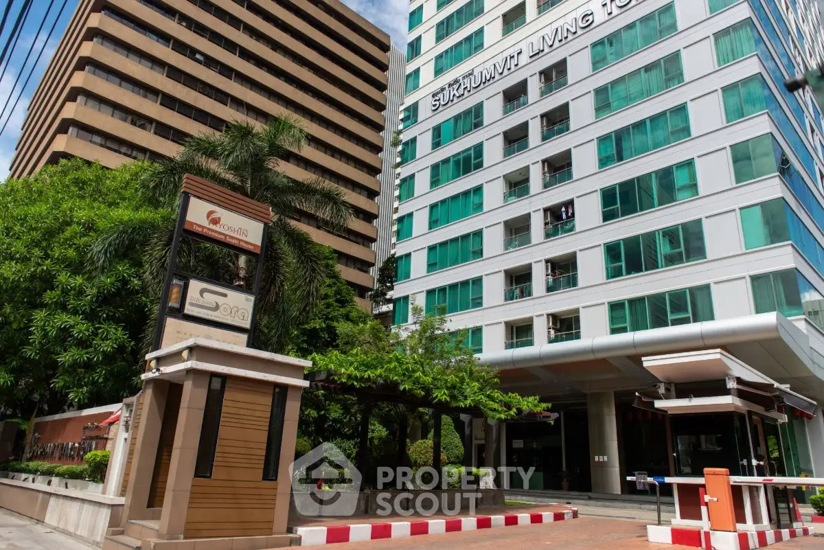 Modern high-rise building with lush greenery and secure entrance in urban setting.