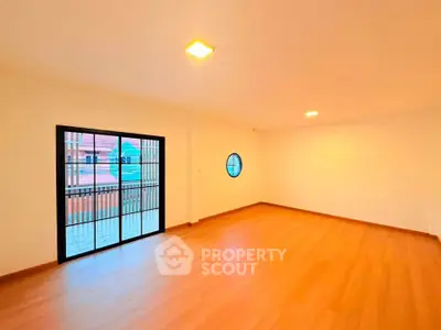 Spacious empty room with wooden flooring and balcony access, ideal for customization.