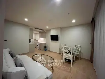 Modern living room with open kitchen, stylish furniture, and cozy ambiance in a contemporary apartment.