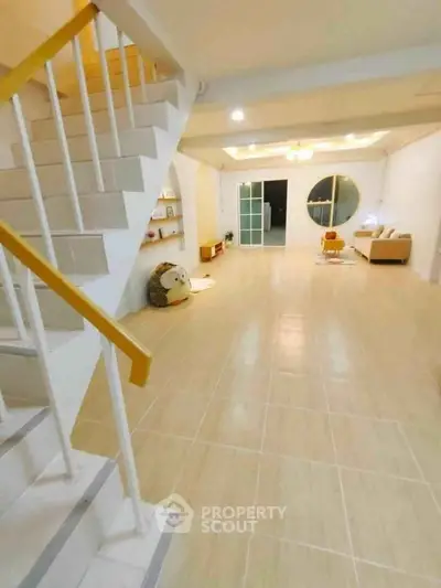 Spacious modern living room with staircase and cozy seating area, ideal for family gatherings.