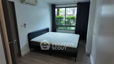 Cozy bedroom with large window and air conditioning in modern apartment.