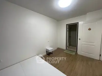 Minimalist bedroom with wooden flooring and attached bathroom