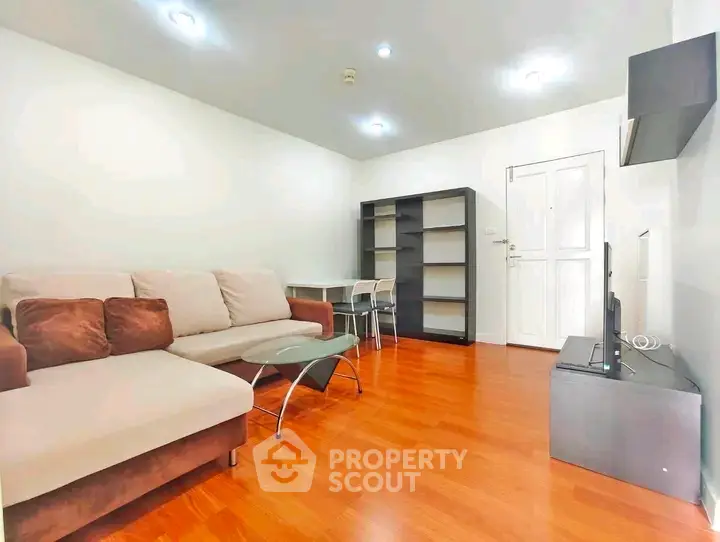 Spacious living room with modern sofa and wooden flooring in a bright apartment.