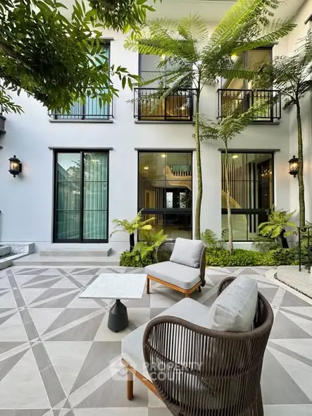 Luxurious garden patio with modern furniture and lush greenery in a stylish residential setting.