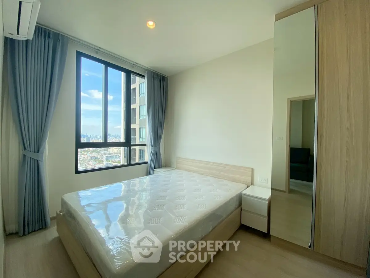 Bright bedroom with large window and city view in modern apartment