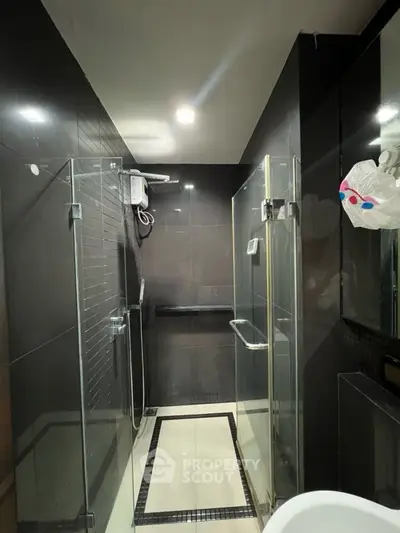 Modern bathroom with sleek glass shower and dark tile design.