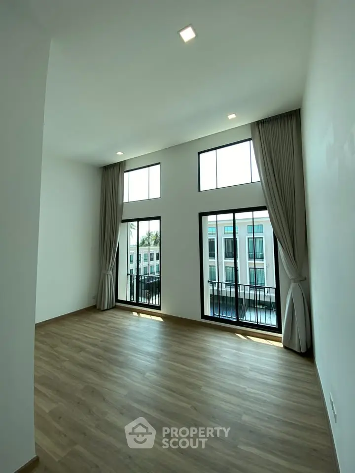 Spacious modern living room with high ceilings and large windows offering natural light and a view.