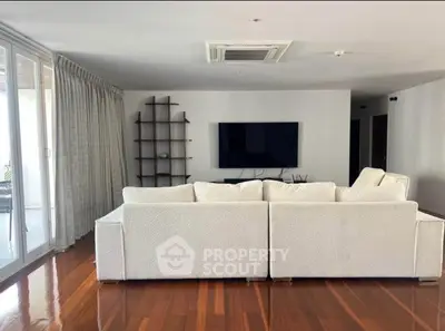 Spacious modern living room with sleek white sofa and large TV, perfect for relaxation.