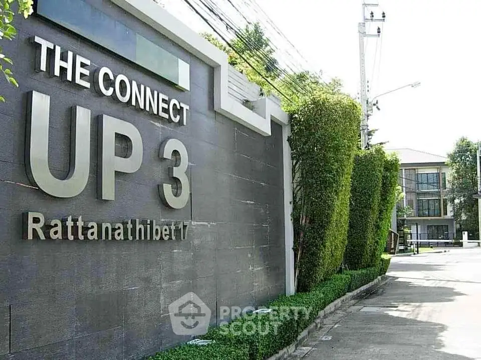 Modern residential complex entrance with sleek design and lush greenery