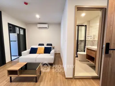 Modern apartment interior with cozy living room and adjacent bathroom, featuring stylish furniture and wooden flooring.