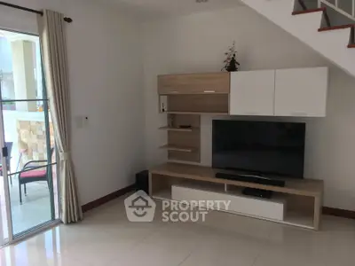 Modern living room with sleek TV unit and sliding glass doors to balcony.