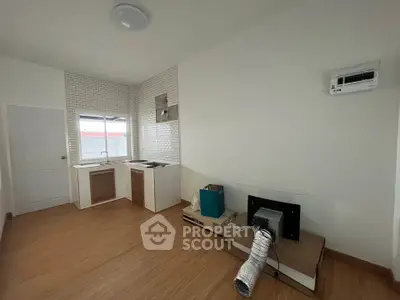 Modern kitchen with open layout and wooden flooring, featuring a large window and sleek cabinetry.