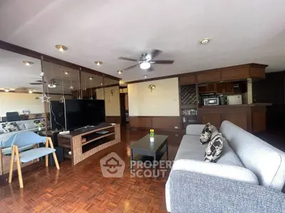 Spacious living room with modern decor and wooden flooring, featuring a cozy seating area and entertainment setup.