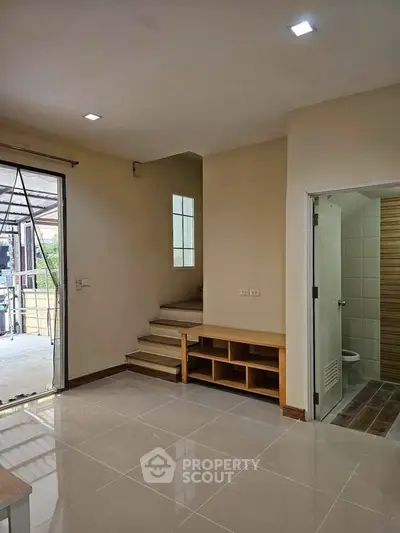 Modern interior with staircase and open layout, featuring sleek tile flooring and natural light.