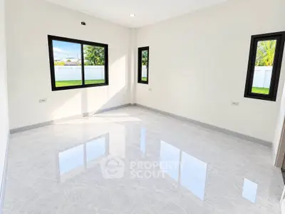 Spacious empty room with large windows and glossy tiled floor, offering abundant natural light and garden view.